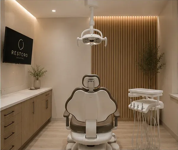 A Restoro operatory — dental chair, wood-slat wall, and the ring-logo screen